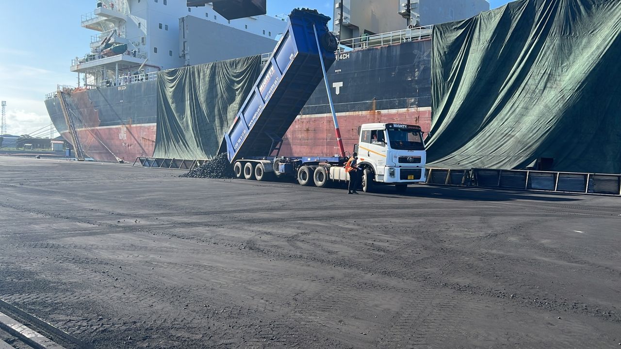 Truck tipping coal alongside vessel